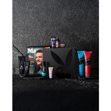 Schwarze Geschenkbox mit großem Playboy-Logo, umgeben von verschiedenen Pflegeprodukten und einer Ausgabe des Magazins "Maxim".